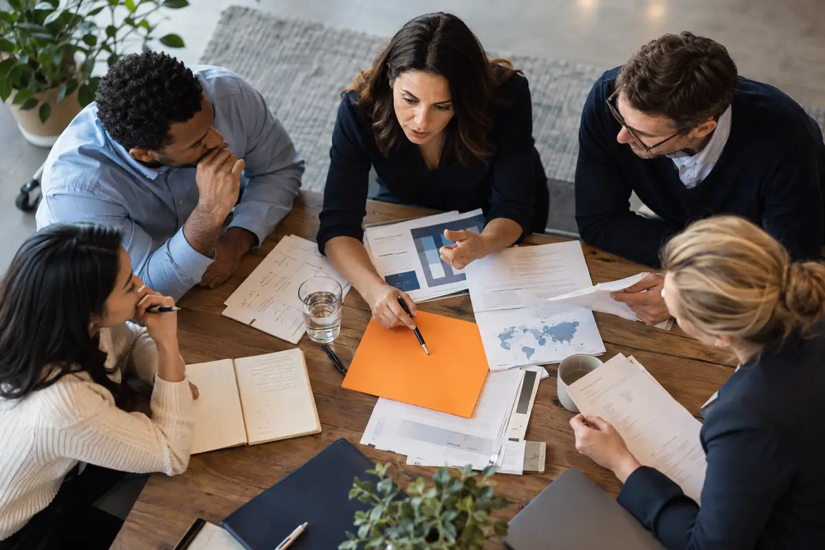 An experienced operations leader walking through an active consulting office speaking with a team lead, candid documentary composition.